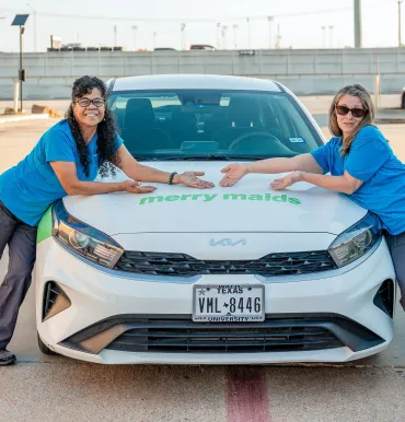 merry maids standing in front of a branded vehicle